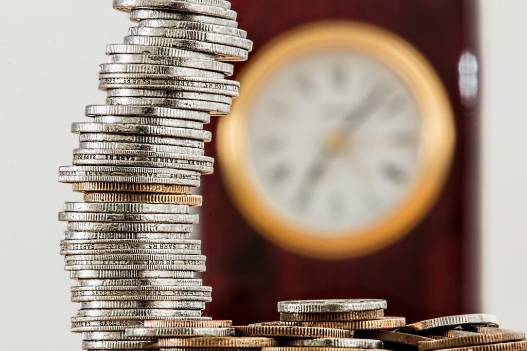 Image of coins stacked with a clock in background